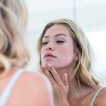 Woman looking in mirror with hands on chin