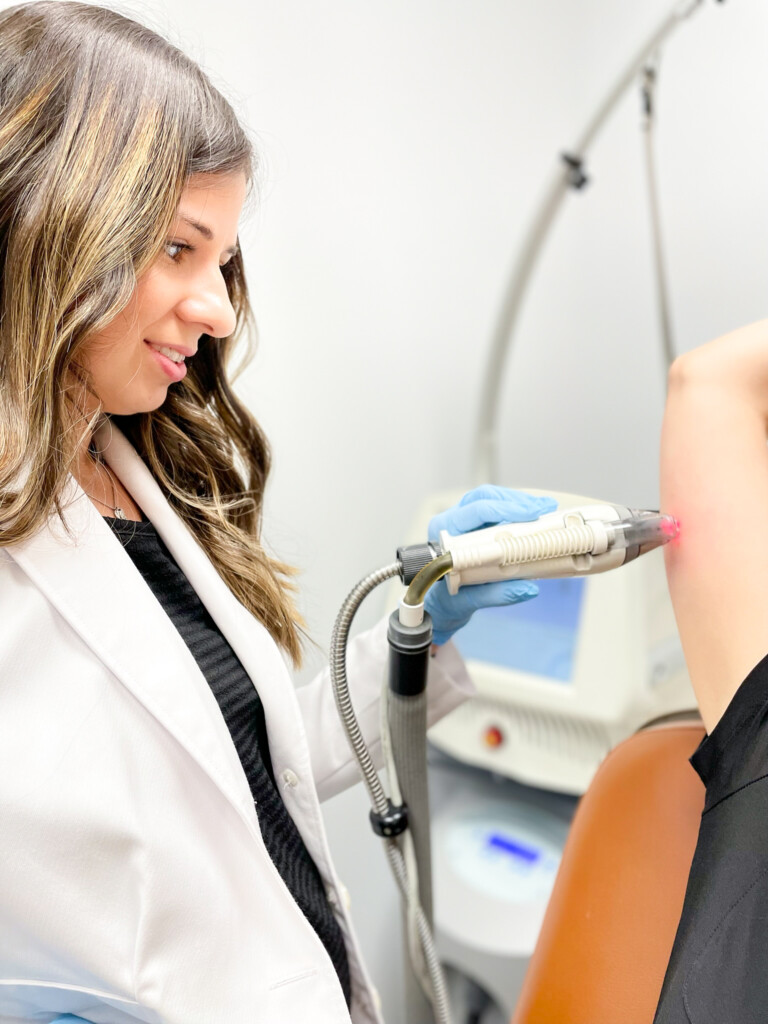 Angela Cusumano, PA-C, performs a Fraxel laser treatment on a patient’s upper arm using a handheld laser device.