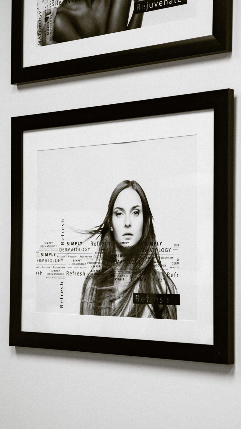 A framed black-and-white portrait of a woman displayed on the clinic wall at Simply Derm, featuring subtle text overlays with the Simply Dermatology branding.
