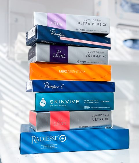 Stack of Juvederm, Restylane, Radiesse, and Skinvive filler boxes used in Botox and filler prejuvenation treatments at Simply Dermatology.