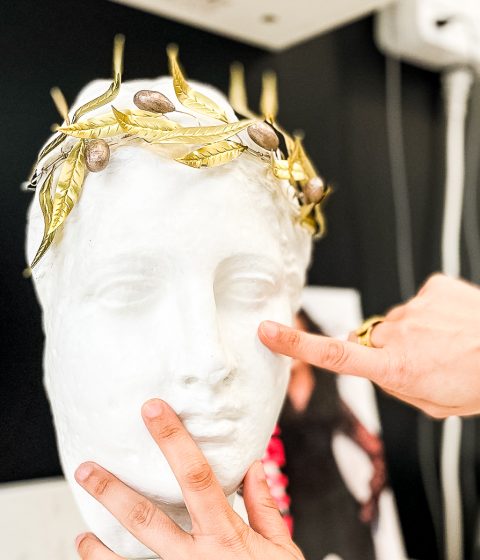 Hands demonstrating facial balance and skin assessment on a sculpted face model