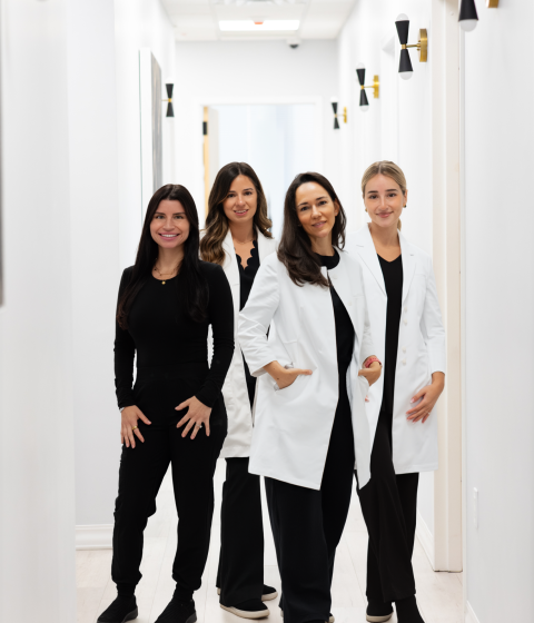 Team of four providers standing in hallway at Simply Dermatology office.