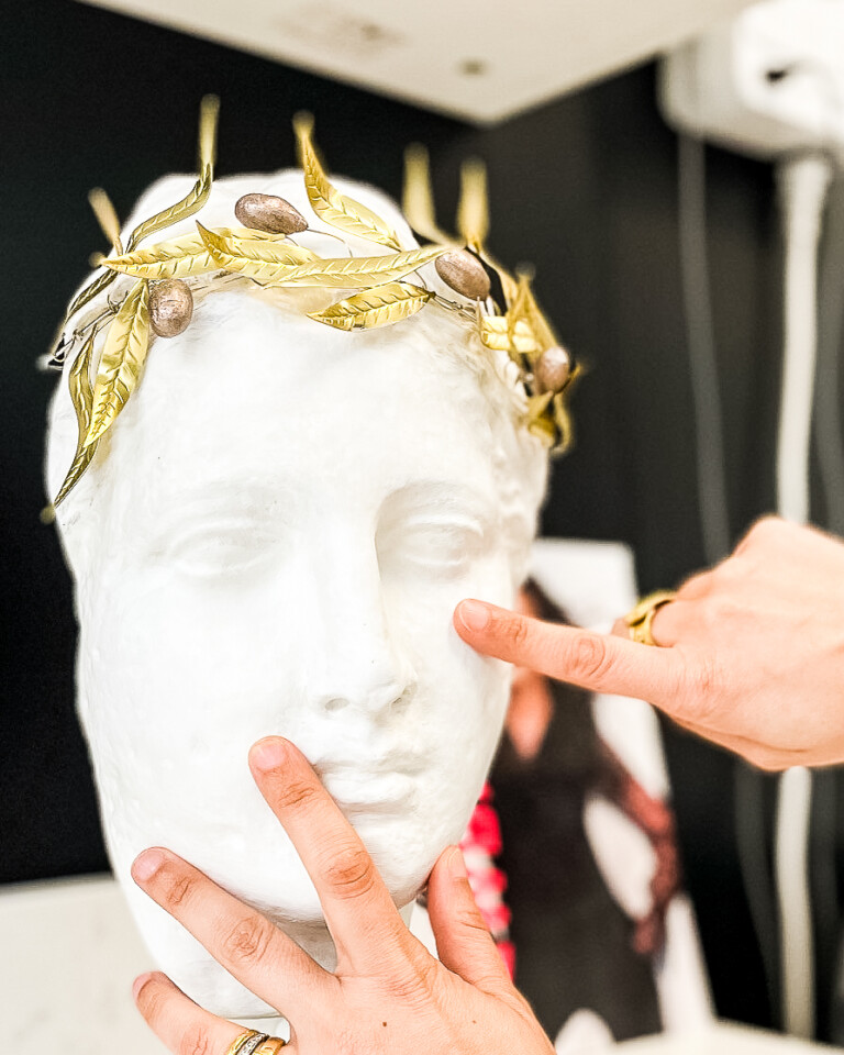 Hands demonstrating facial balance and skin assessment on a sculpted face model