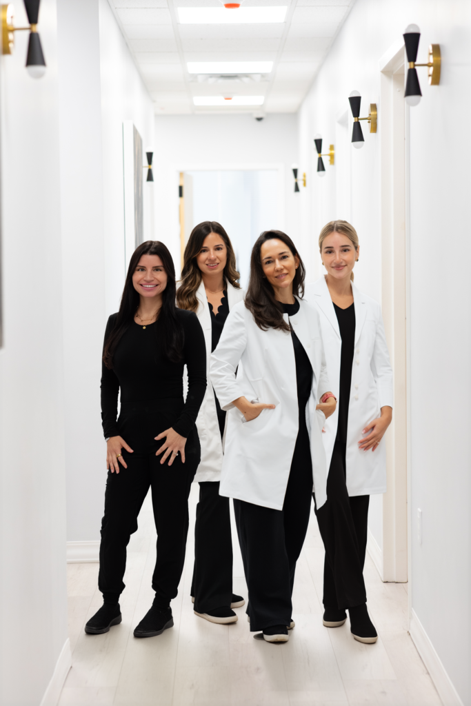 Team of four providers standing in hallway at Simply Dermatology office.