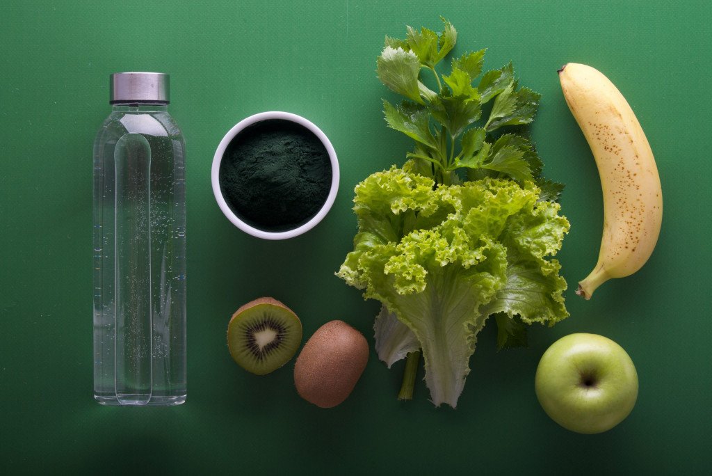assorted fruits and veggies and water bottle on green surface